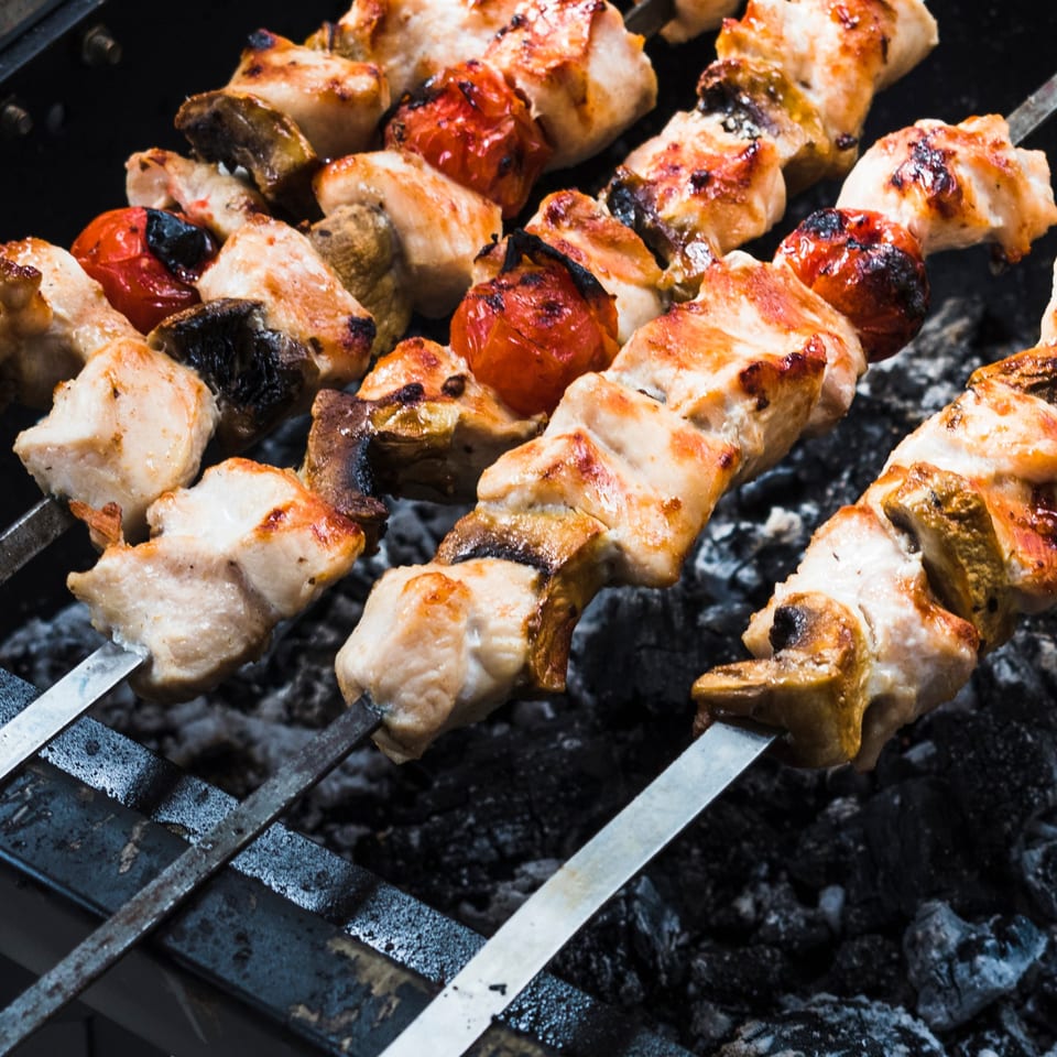 Chicken and vegetable skewers grilling over hot coals at Alice's Bar-B-Que.