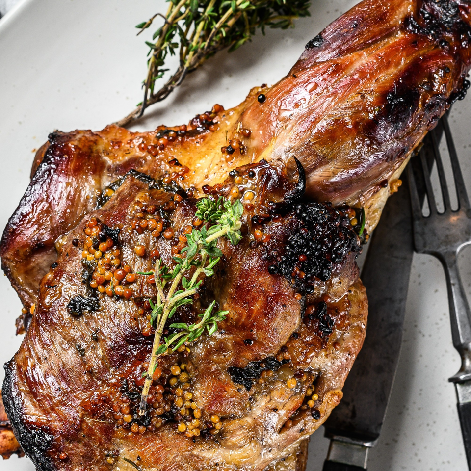 Close-up of a glistening, grilled Alice's Bar-B-Que meat cut with herbs and mustard seeds.